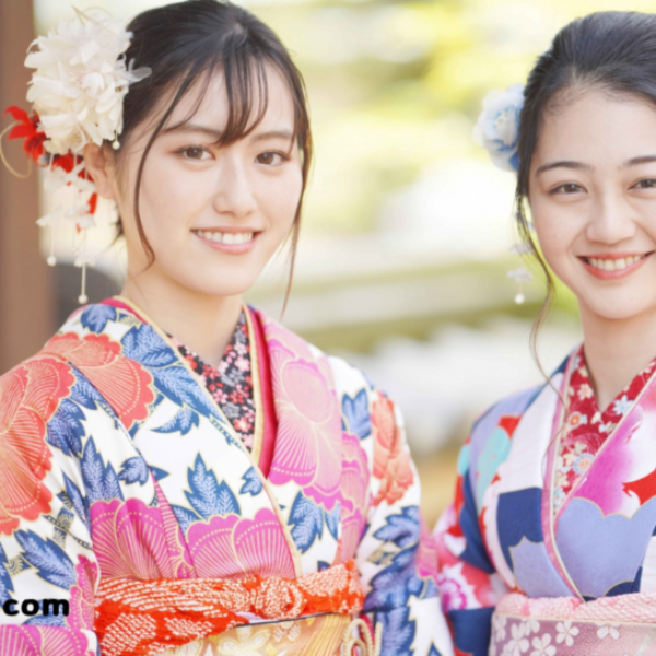 Two women wearing colorful traditional Japanese kimonos with floral patterns and hair accessories, smiling at the camera.