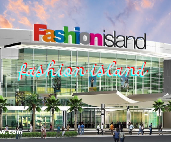 An exterior view of a shopping center named "Fashion Island," with a colorful logo at the top of the building. Below, there are glass windows, palm trees, and people walking around the entrance.