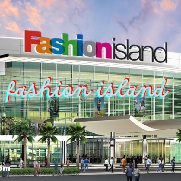 An exterior view of a shopping center named "Fashion Island," with a colorful logo at the top of the building. Below, there are glass windows, palm trees, and people walking around the entrance.